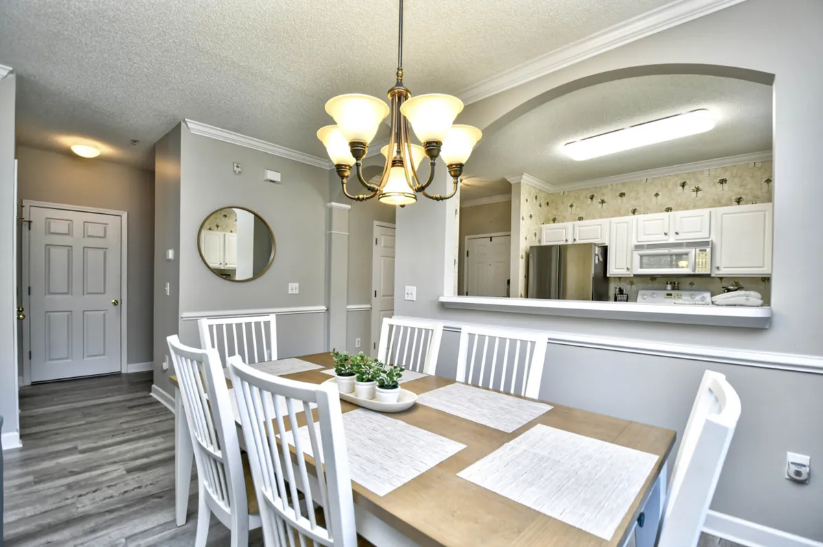 A cozy dining area with a dining table set beneath a chandelier, adjacent to a kitchen pass-through. The setup invites family meals, casual gatherings, and easy movement between cooking and dining spaces, supported by warm lighting and a welcoming ambiance.