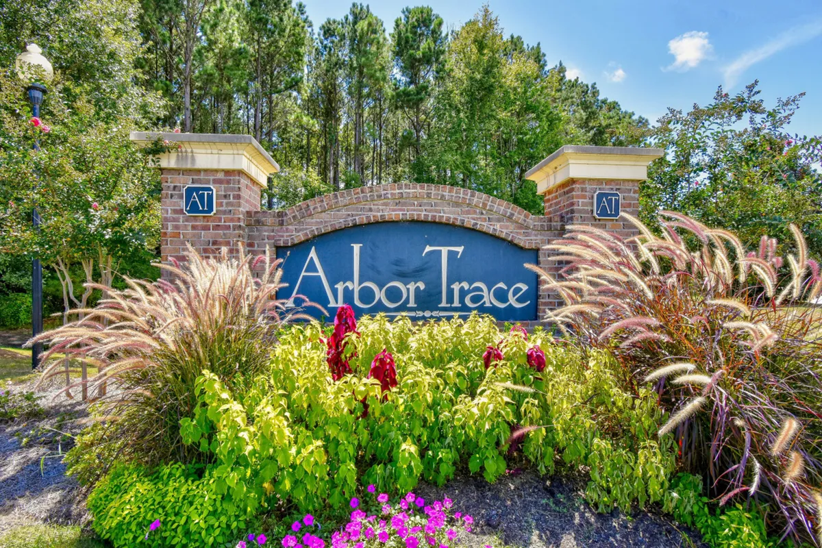 An exterior shot of the Arbor Trace community sign surrounded by landscaped flower beds and a welcoming brick structure. The vibrant gardens and communal feel are visible, suggesting opportunities for walks and social moments within the community.
