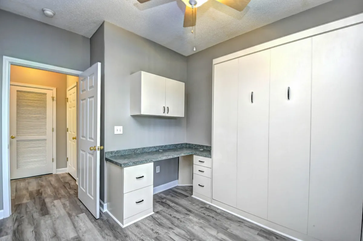 A dedicated work nook with a built-in desk and cabinetry, illuminated by ample natural light. The minimalistic setup is designed for productivity, offering a quiet retreat for remote work or study within the home.