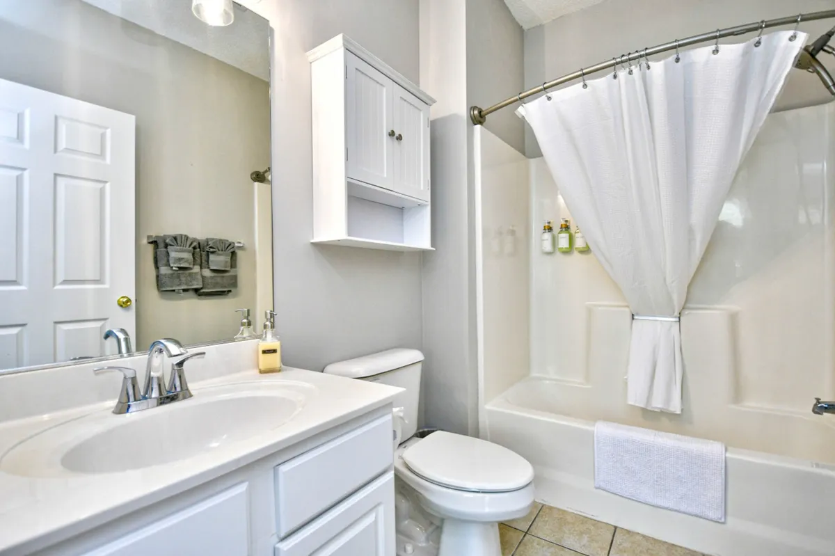 A bright, elegant bathroom with a vanity and sink, large mirror, and a walk-in shower area. The design is modern and inviting, ideal for self-care routines and refreshing showers after a busy day.