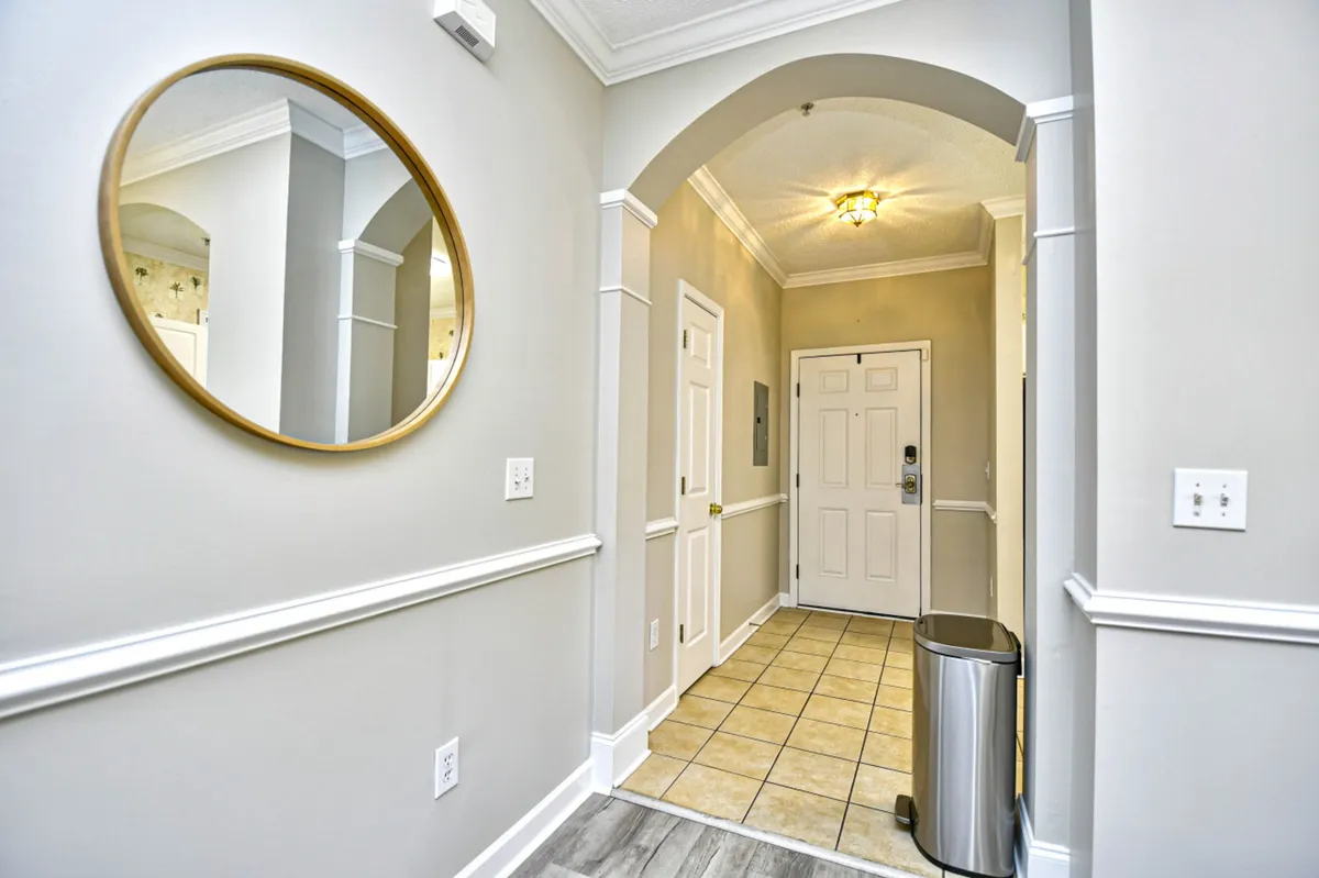 This image shows the entryway of the condo, featuring a round mirror, tile flooring, the entrance door, and a welcoming, organized atmosphere. The setting hints at returning from an outing, ready to relax or prepare for the next adventure.