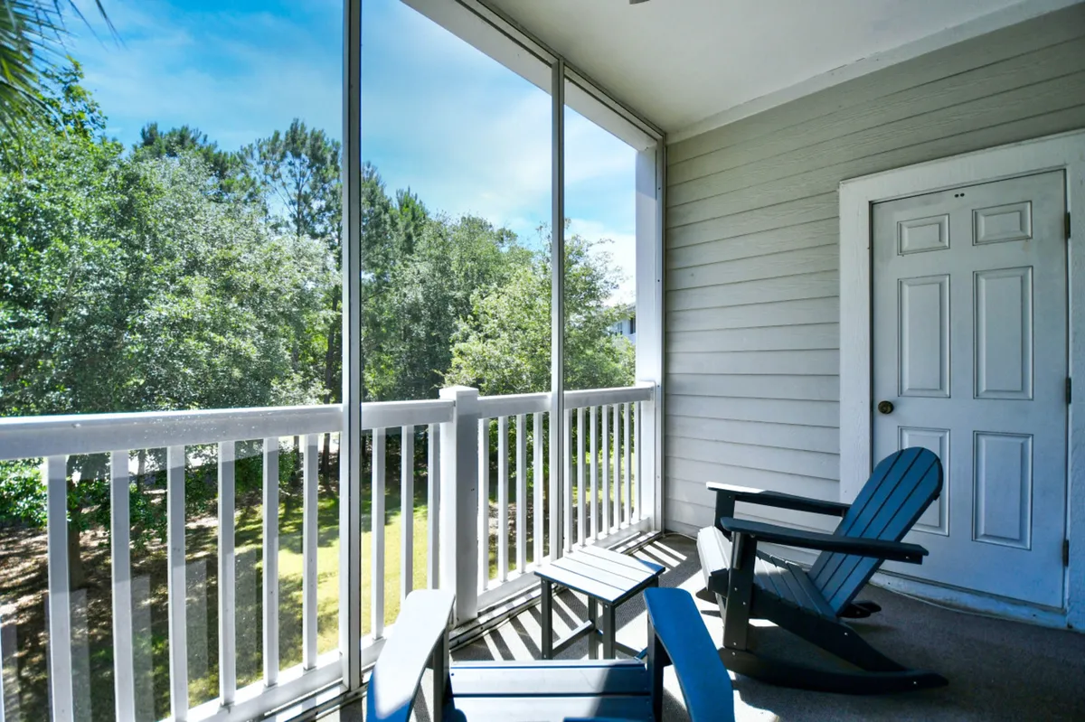 A peaceful exterior patio featuring Adirondack chairs, a glass railing, and lush green foliage, creating a tranquil spot for relaxing or unwinding after a day on the course.