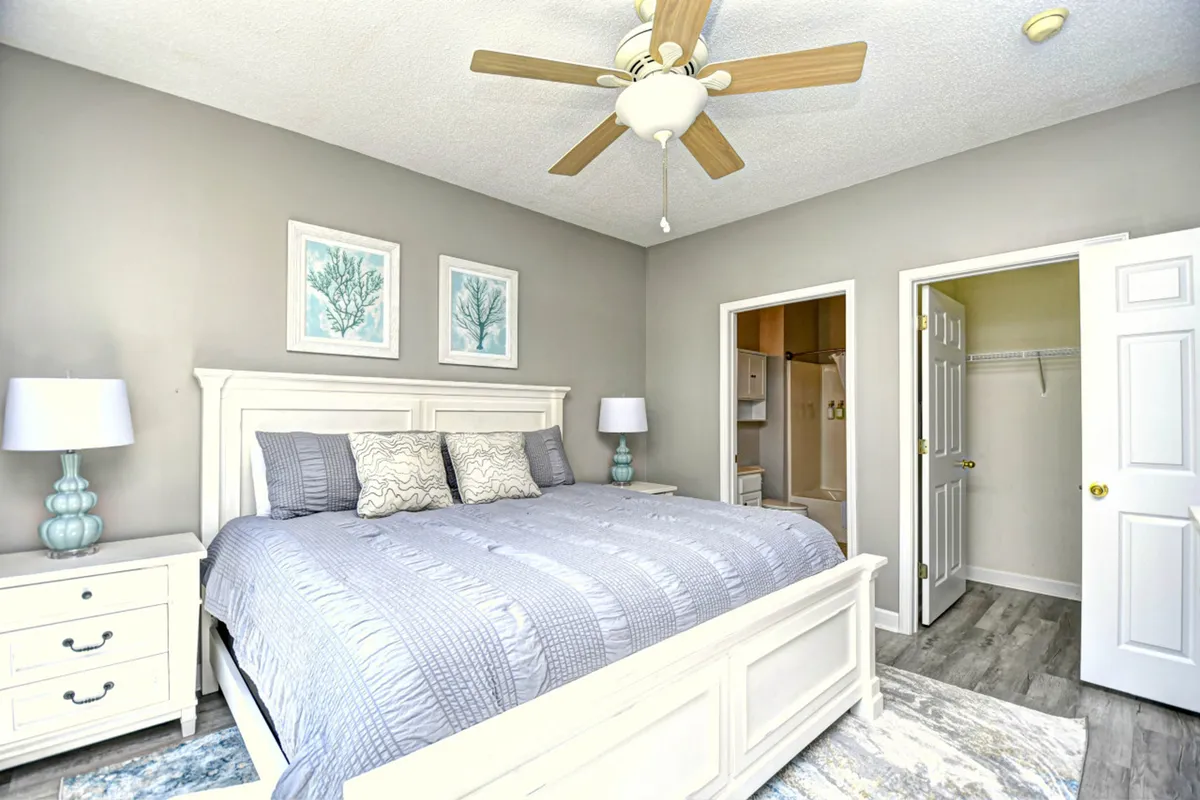 This image presents a large bed with decorative pillows, flanked by calming blue bedside lamps and complemented by framed wall art. The ambiance is tranquil, creating an inviting atmosphere ideal for restful sleep or quiet relaxation.